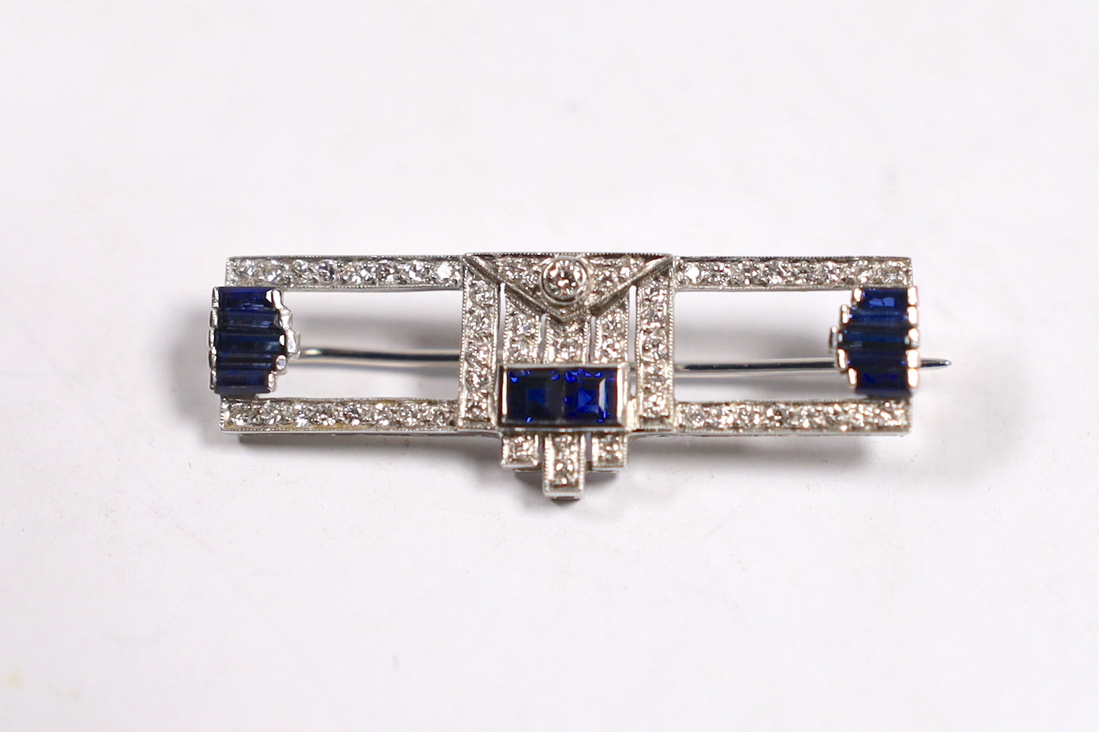 A 1980's Art Deco style Garrard 18ct white gold, sapphire and diamond cluster set bar brooch, 35mm, gross weight 4.4 grams.